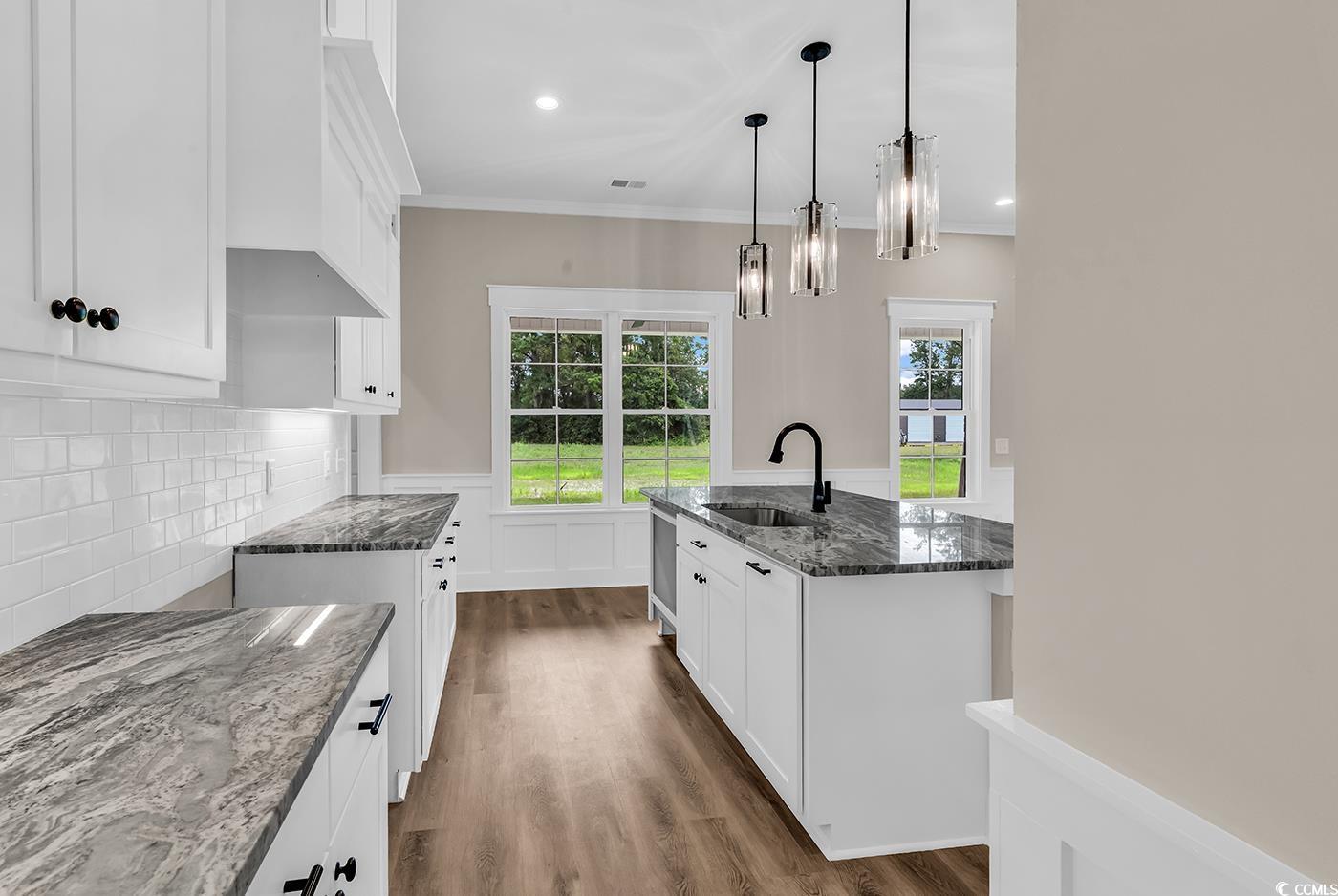 713 Horry Road Aynor, SC 29511 - Photo 15 of 40 Kitchen featuring white cabinetry, dark stone countertops, a kitchen island with sink, dark wood-style floors, and ornamental molding