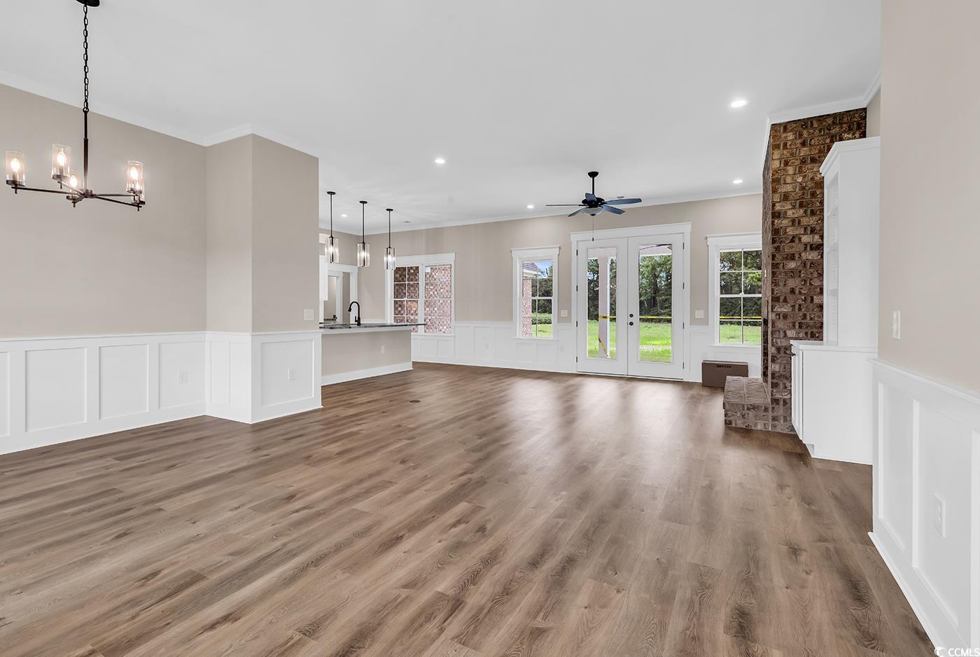 713 Horry Road Aynor, SC 29511 - Photo 2 of 40 Unfurnished living room with a wainscoted wall, a decorative wall, a chandelier, ornamental molding, and dark wood finished floors