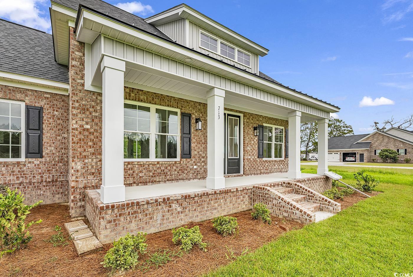 713 Horry Road Aynor, SC 29511 - Photo 39 of 40 Entrance to property featuring covered porch, brick siding, a shingled roof, and a yard
