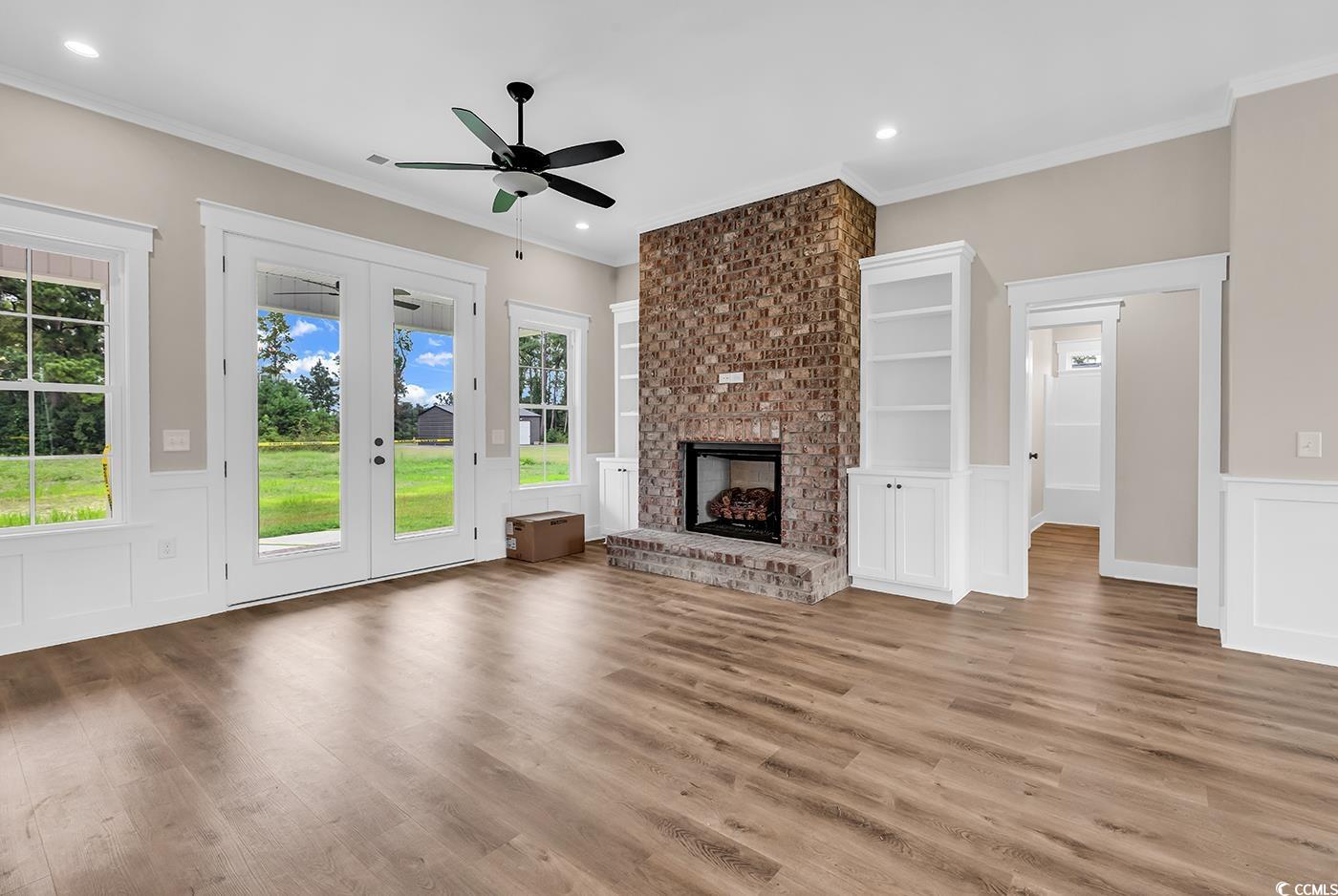 713 Horry Road Aynor, SC 29511 - Photo 6 of 40 Unfurnished living room featuring ornamental molding, wainscoting, a decorative wall, wood finished floors, and french doors