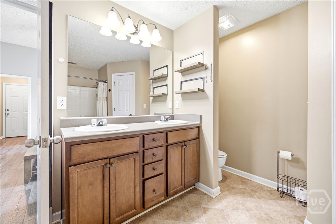 121 Crestview Drive Carnesville, GA 30521 - Photo 15 of 28 Bathroom featuring a dual vanity with wood-finish cabinetry and light-toned countertops, a large framed mirror, and warm neutral wall paint