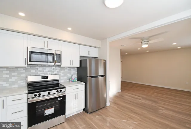 a kitchen with a refrigerator stove and wooden floor