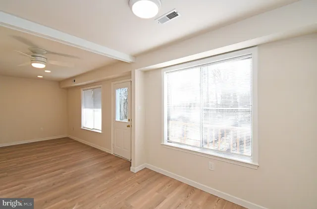 a view of an empty room with wooden floor and a window