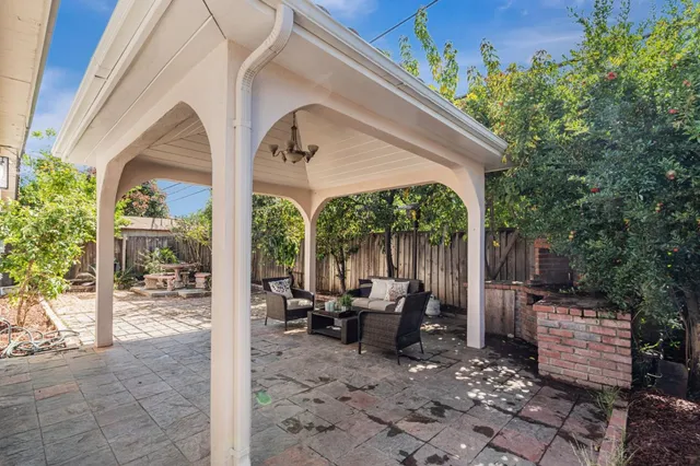 a view of a patio with table and chairs potted plants and floor to ceiling window and tree
