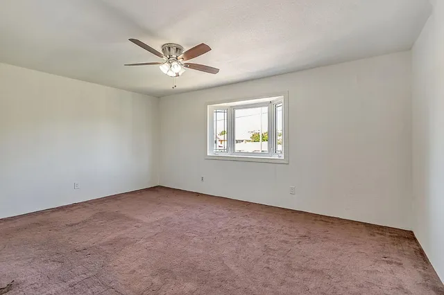 an empty room with a window and a fan
