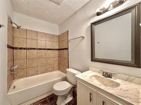 a bathroom with a granite countertop sink toilet mirror and bathtub
