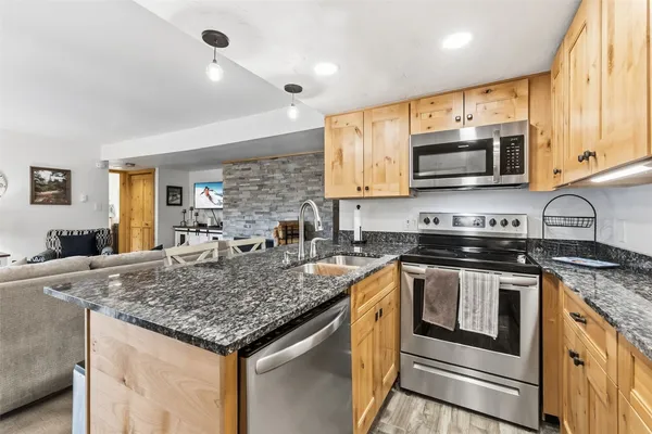 a kitchen with stainless steel appliances granite countertop a sink stove microwave and refrigerator