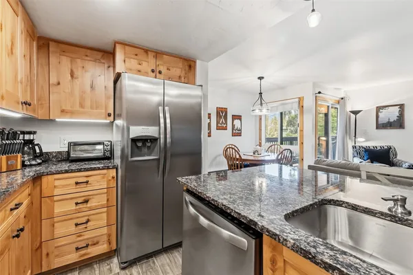 a kitchen with stainless steel appliances granite countertop a sink a refrigerator and wooden cabinets