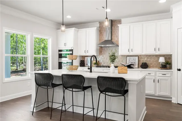 a kitchen with stainless steel appliances kitchen island granite countertop a table and a white cabinets