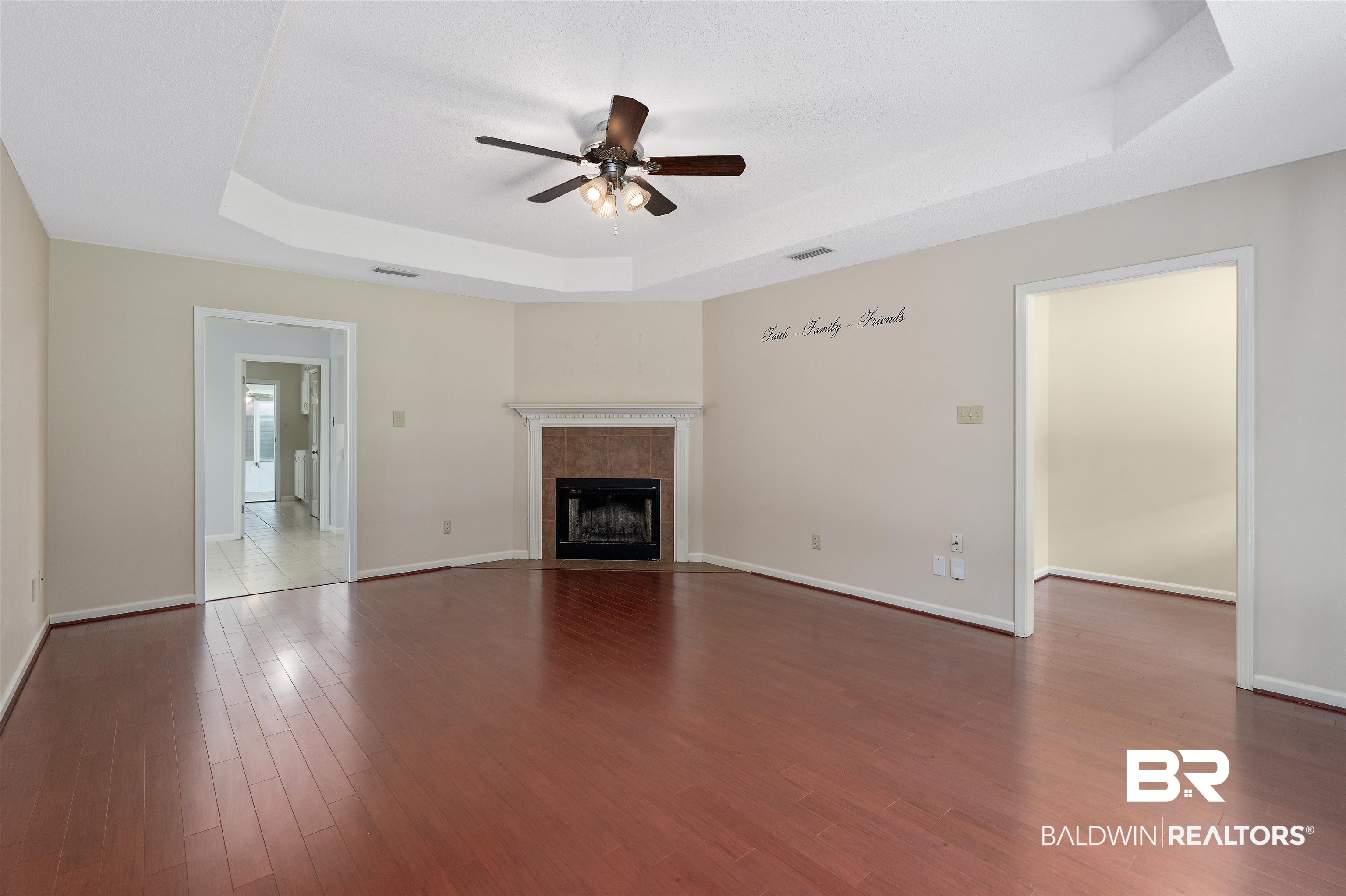 25779 Austin Road Daphne, AL 36526 - Photo 14 of 30 Unfurnished living room featuring a tray ceiling, ceiling fan, wood finished floors, and baseboards