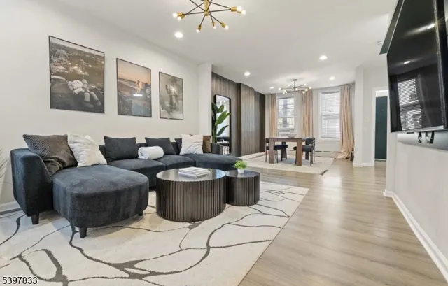 a living room with couches and kitchen view with wooden floor