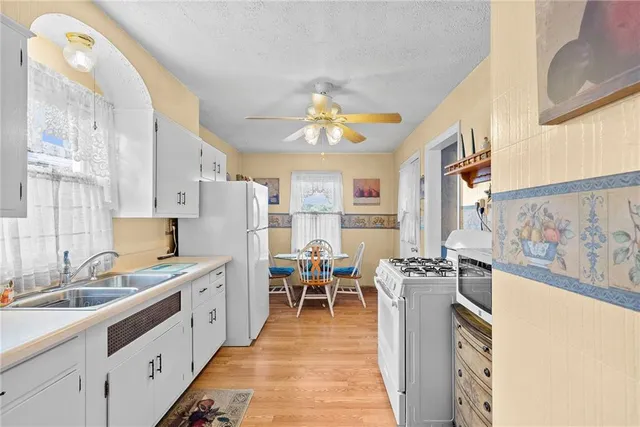 a kitchen with stainless steel appliances granite countertop a stove oven a sink dishwasher and white cabinets with wooden floor