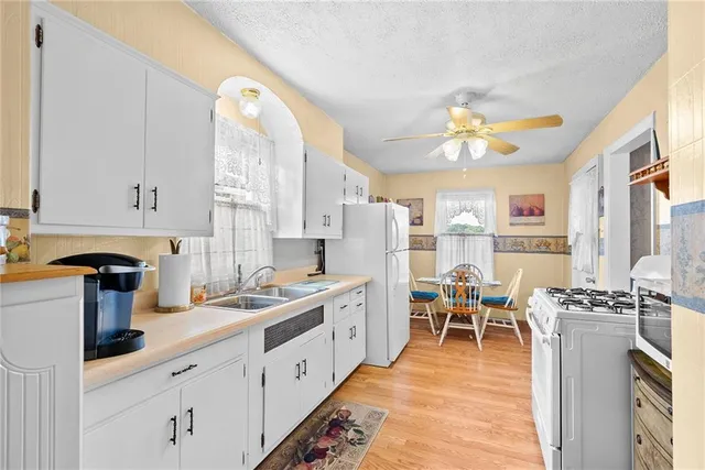 a kitchen with stainless steel appliances a stove a sink dishwasher and white cabinets with wooden floor