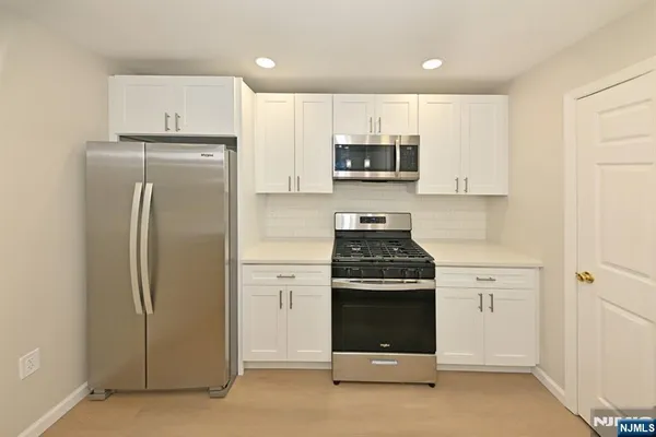 a kitchen with stainless steel appliances white cabinets and a refrigerator