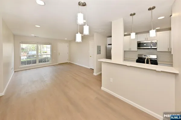an open kitchen with large white cabinets and stainless steel appliances