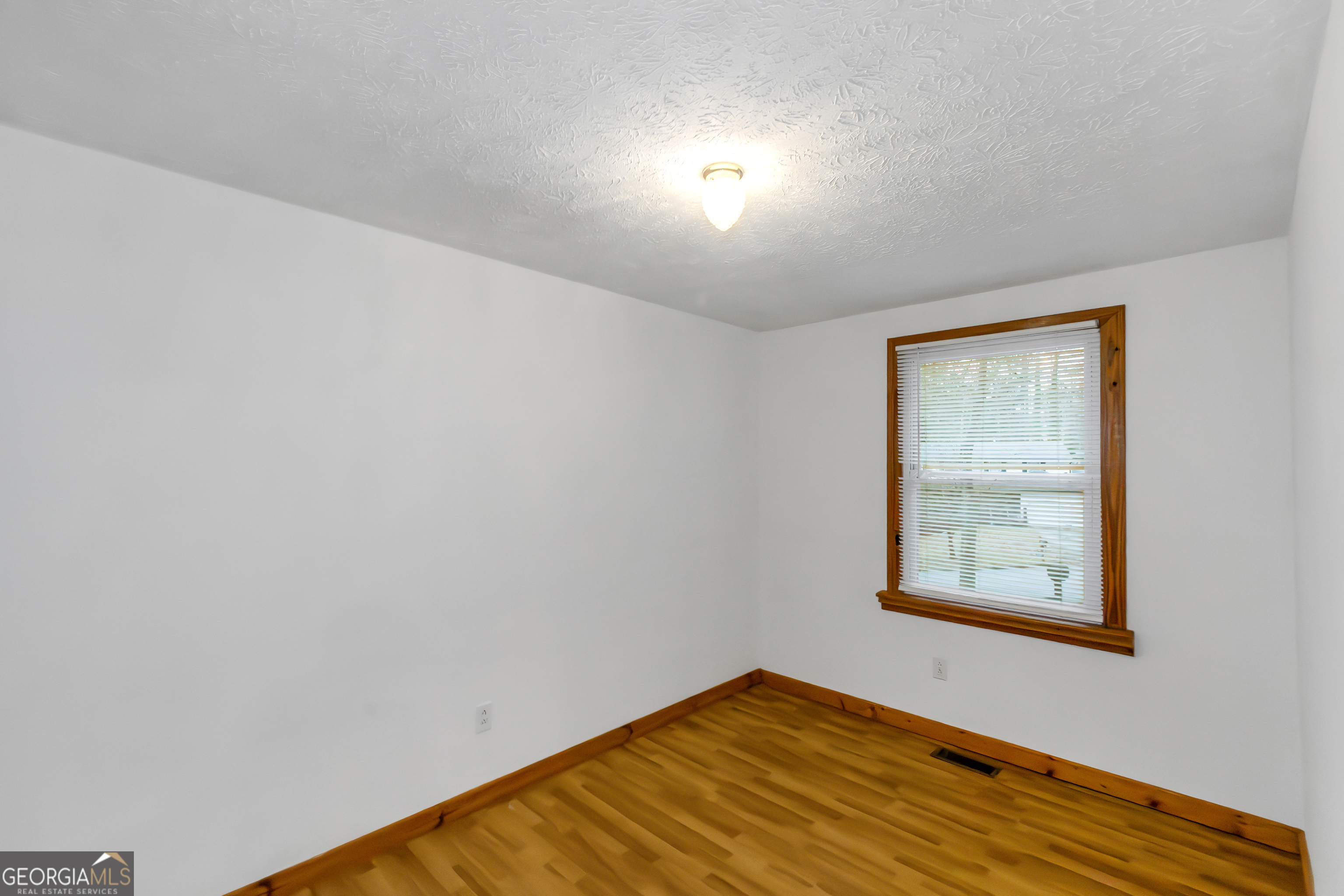 7600 Suwannee Court Jonesboro, GA 30236 - Photo 21 of 35 a view of an empty room with window and wooden floor