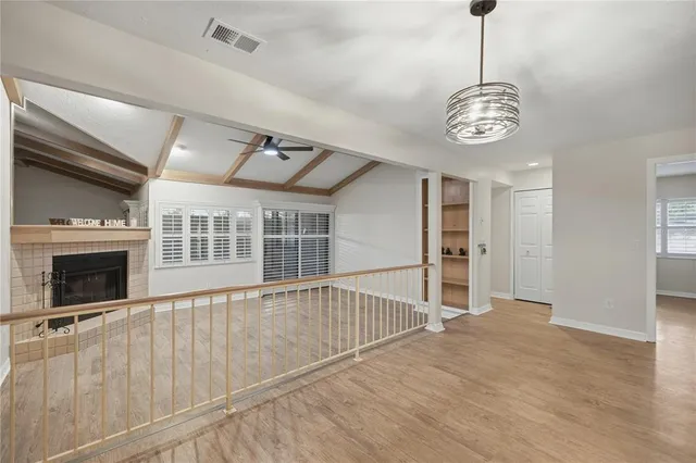 a view of a livingroom with a fireplace a ceiling fan and windows
