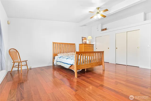 a view of a bedroom with wooden floor & a window