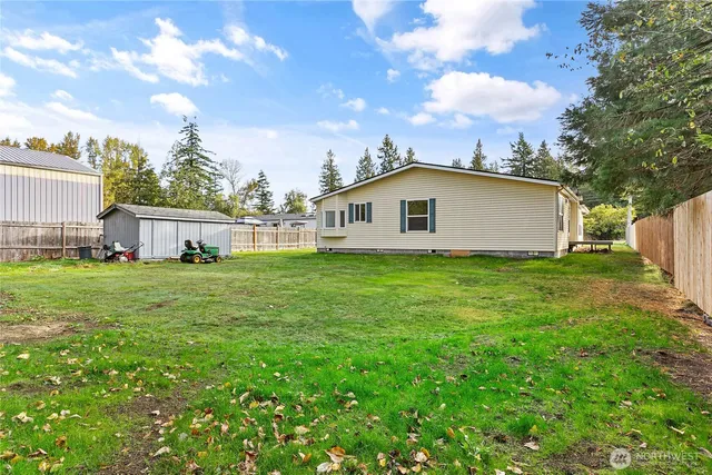 a view of a white house with a yard and wooden fence