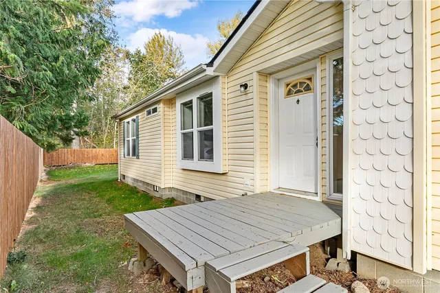 a view of a yard in front of a house with plants and large trees