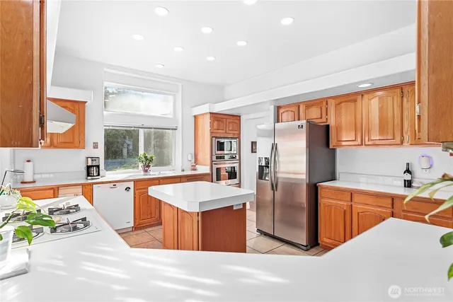 a large kitchen with stainless steel appliances kitchen island granite countertop a refrigerator and a sink
