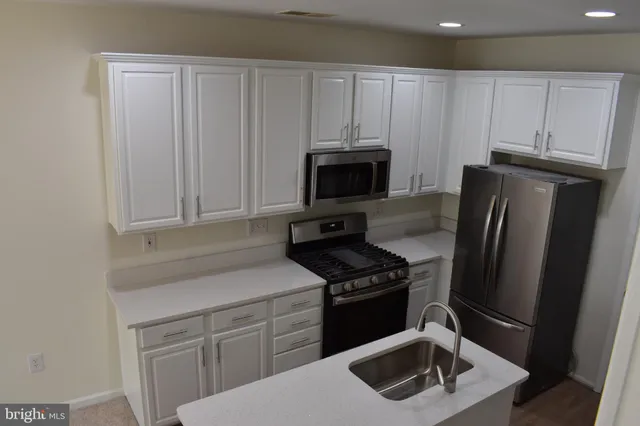a kitchen with white cabinets sink and stainless steel appliances