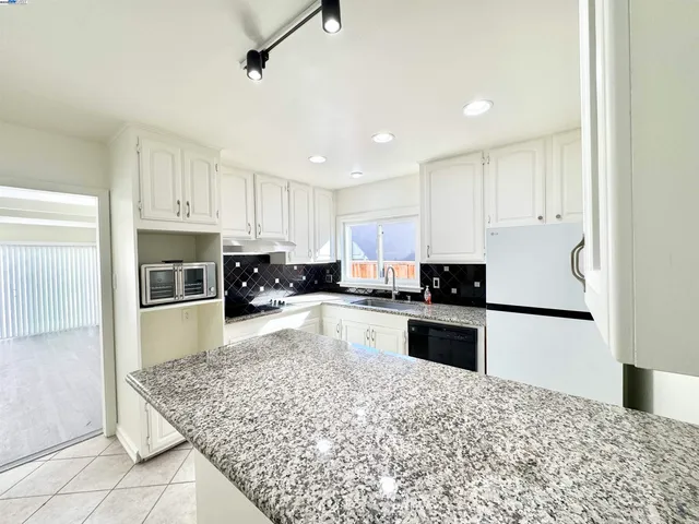 a kitchen with granite countertop a refrigerator oven a sink and dishwasher