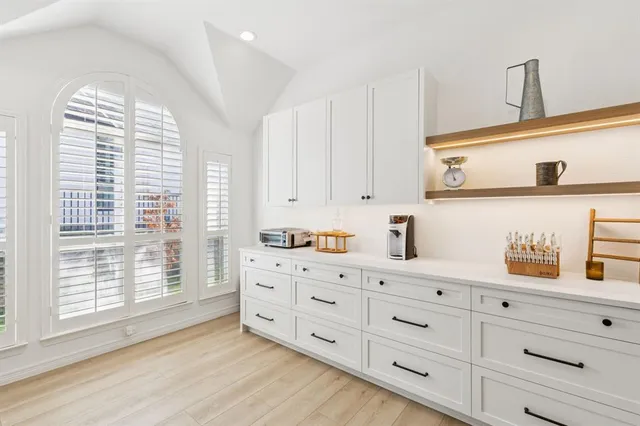 a kitchen with stainless steel appliances a stove a sink a microwave a dining table and chairs with wooden floor