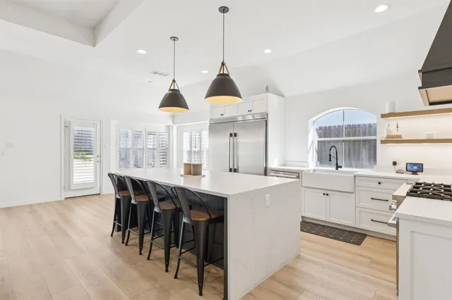 a kitchen with stainless steel appliances a dining table chairs stove and white cabinets