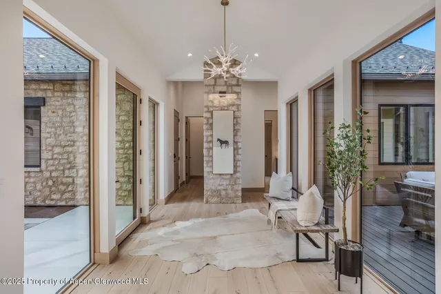 a view of a livingroom with chandelier front door and wooden floor
