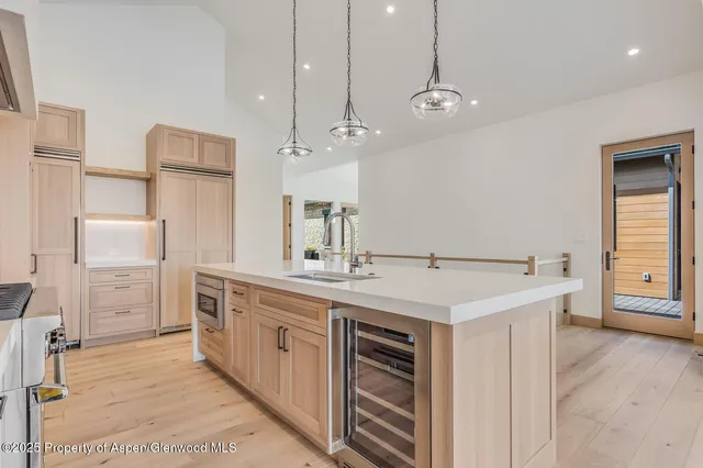 a view of a hallway with wooden floor and a kitchen