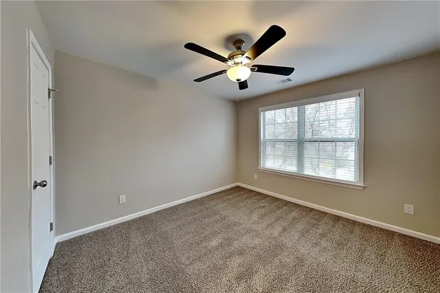 a view of an empty room with chandelier fan and a window