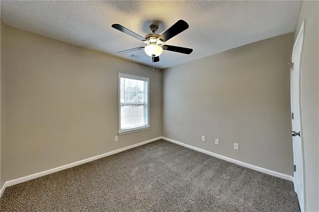 an empty room with window and ceiling fan
