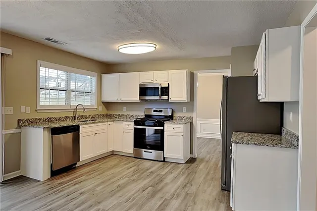 a kitchen with granite countertop a refrigerator stove top oven and sink