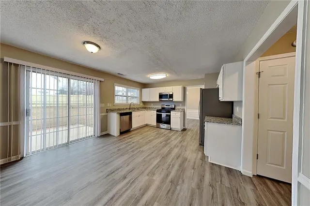 a room with stainless steel appliances wooden floors and large window