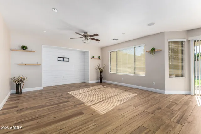 a view of empty room with wooden floor and fan