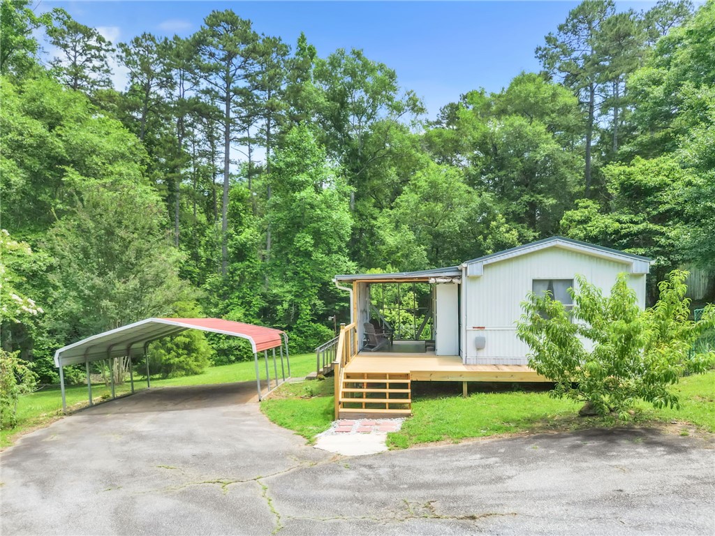 506 Charlies Creek Road Iva, SC 29655 - Photo 4 of 28 A quaint residence nestled amidst lush trees, featuring a generous deck and a convenient carport.