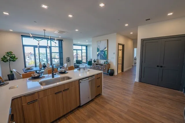 a large kitchen with stainless steel appliances a large counter top a sink and a refrigerator