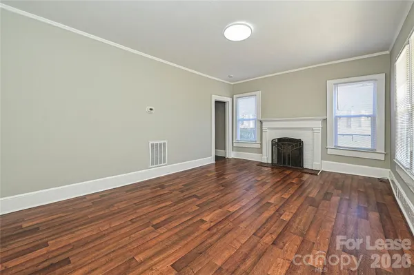 a view of empty room with wooden floor and fireplace