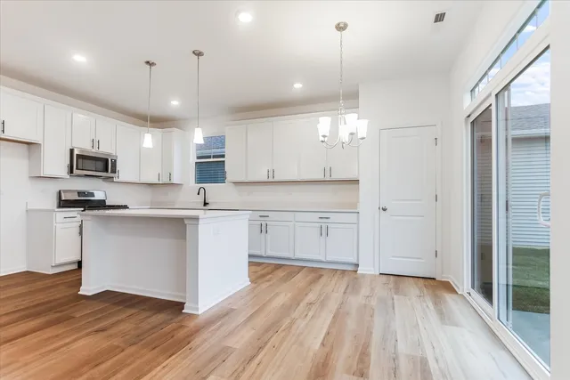 a large kitchen with cabinets wooden floor and stainless steel appliances