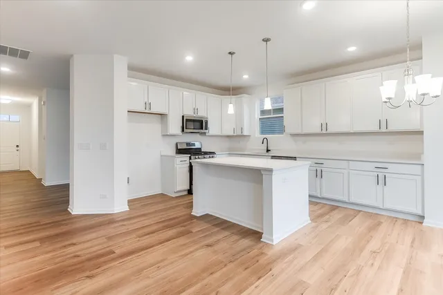 a kitchen with white cabinets stainless steel appliances and wooden floor