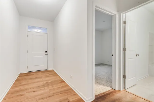 a view of a hallway with wooden floor and a bathroom