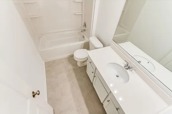 a bathroom with a granite countertop bathtub sink mirror vanity and toilet