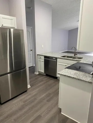 a kitchen with granite countertop a refrigerator and a stove top oven