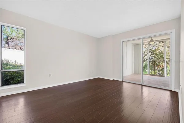 a view of an empty room with wooden floor and a window