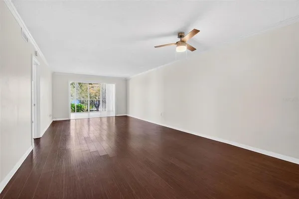 a view of empty room with wooden floor and fan