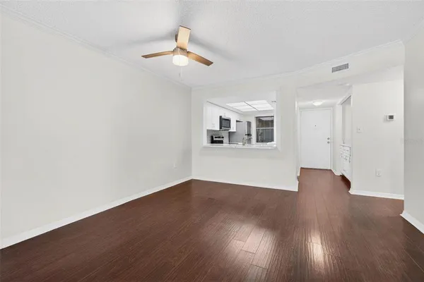 a view of a livingroom with wooden floor a ceiling fan and window