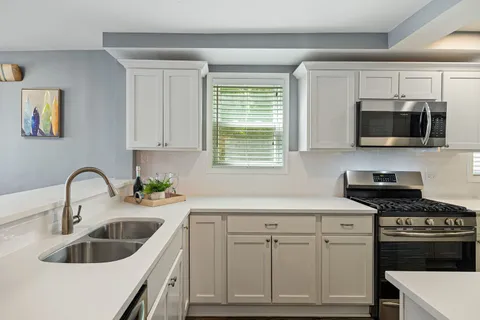 a kitchen with sink a microwave a stove and cabinets