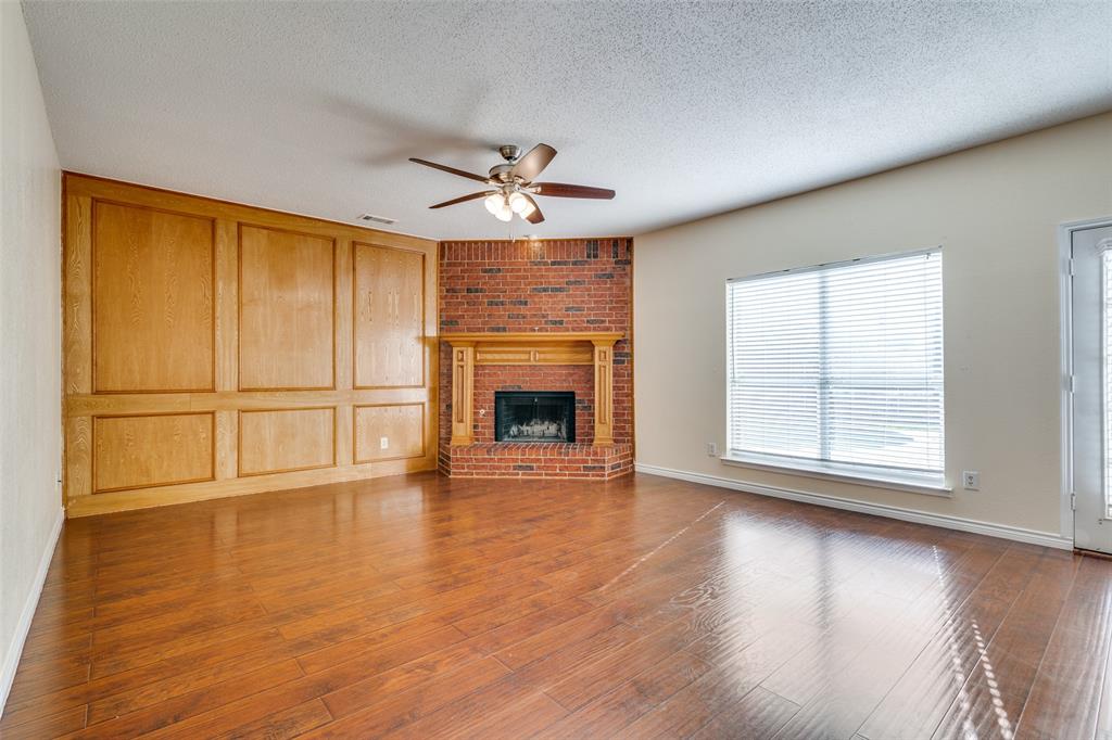 8305 Camden Court Rowlett, TX 75089 - Photo 3 of 18 Unfurnished living room featuring a textured ceiling, a fireplace, ceiling fan, and dark wood-style flooring
