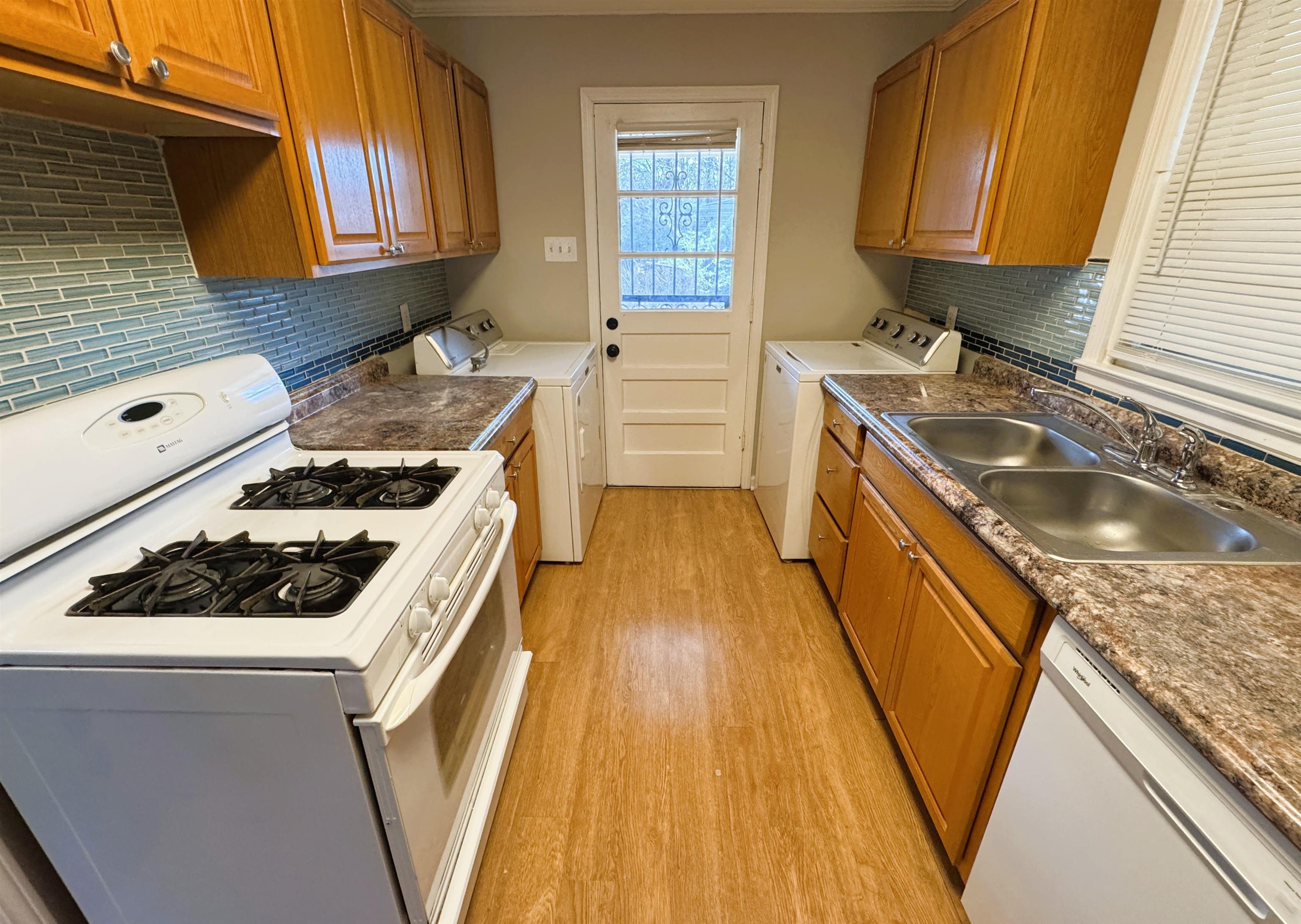 4781 Given Avenue Memphis, TN 38122 - Photo 5 of 15 Kitchen featuring white appliances, washer and clothes dryer, brown cabinets, light wood-style flooring, and tasteful backsplash
